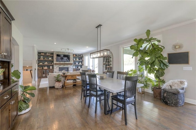 dining area featuring dark wood-type flooring, a fireplace, and ornamental molding