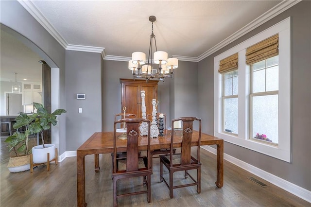 dining room with baseboards, visible vents, a chandelier, wood finished floors, and arched walkways