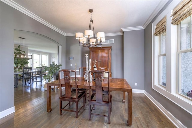 dining area with an inviting chandelier, visible vents, dark wood-style flooring, baseboards, and arched walkways
