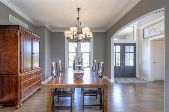 dining area with french doors, ornamental molding, visible vents, a chandelier, and wood finished floors