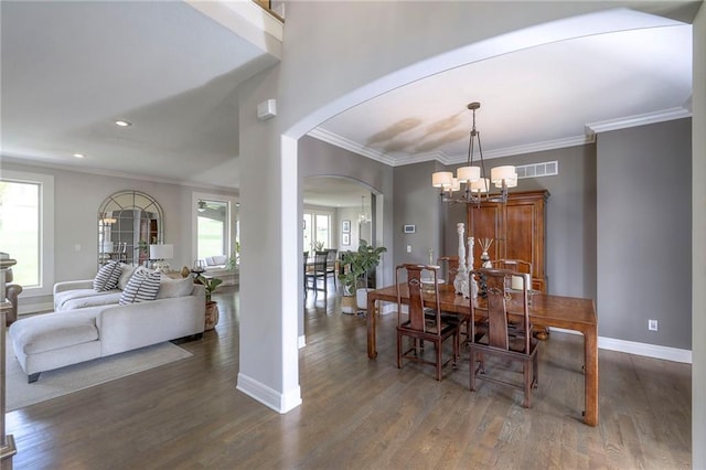 dining space featuring baseboards, visible vents, a chandelier, wood finished floors, and arched walkways
