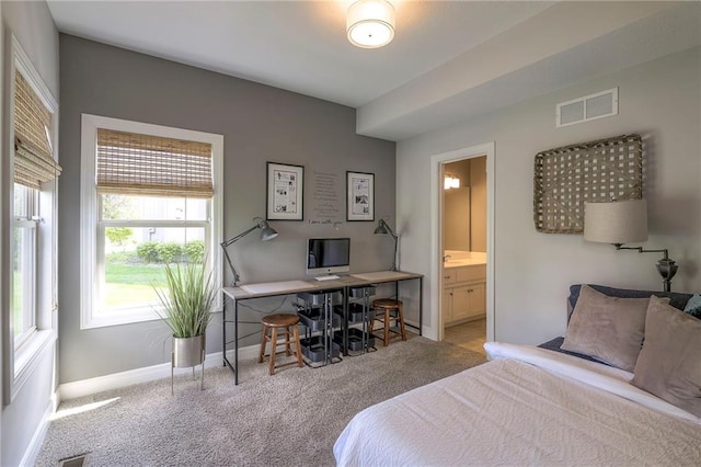 carpeted bedroom featuring baseboards, ensuite bathroom, and visible vents