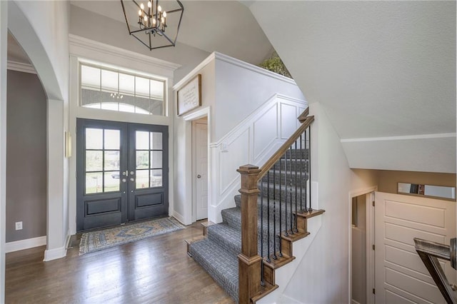 foyer featuring french doors, baseboards, a chandelier, wood finished floors, and stairway