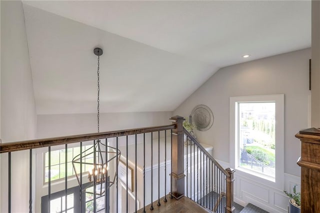 stairs with lofted ceiling, a wealth of natural light, a wainscoted wall, and wood finished floors