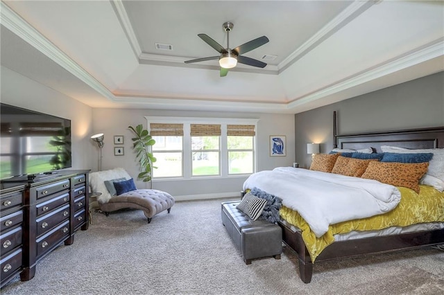 carpeted bedroom featuring a tray ceiling, crown molding, baseboards, and ceiling fan
