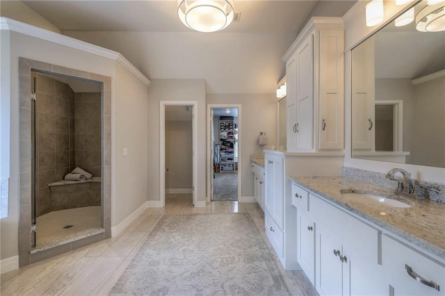 full bath with a walk in closet, vanity, baseboards, and a shower stall