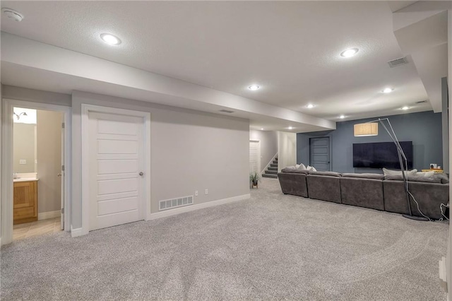 carpeted living area featuring baseboards, stairway, visible vents, and a textured ceiling
