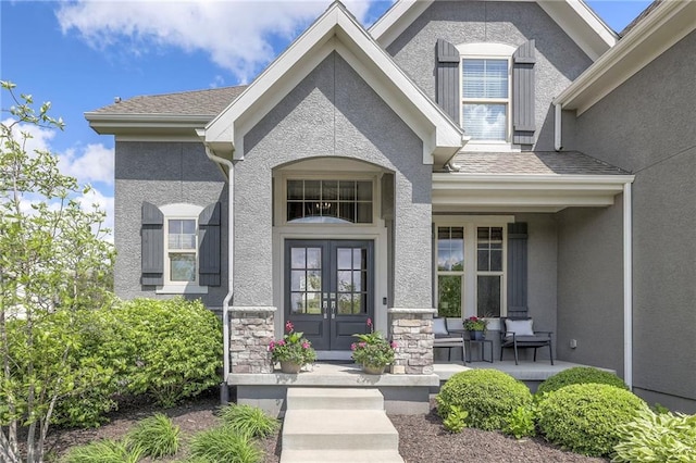 doorway to property with stone siding, stucco siding, french doors, and covered porch