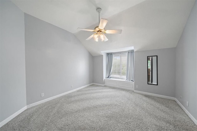 spare room with baseboards, vaulted ceiling, and carpet
