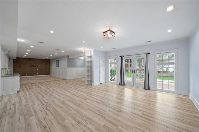 unfurnished living room with recessed lighting, baseboards, a wainscoted wall, and light wood-style floors