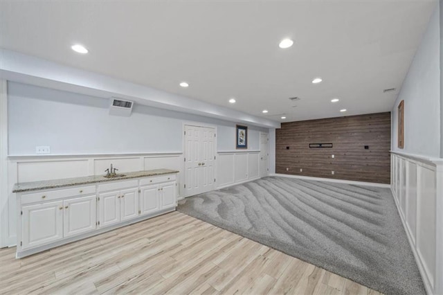finished below grade area featuring a sink, recessed lighting, light wood-style flooring, and visible vents