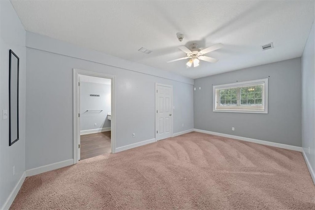 unfurnished bedroom with visible vents, a ceiling fan, baseboards, and light colored carpet