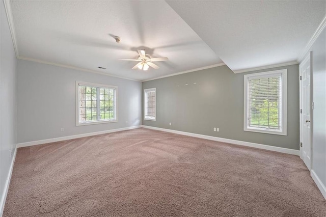 carpeted spare room with baseboards, ornamental molding, and a ceiling fan