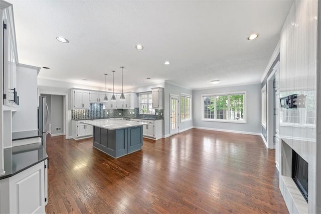 kitchen with ornamental molding, decorative backsplash, baseboards, a center island, and recessed lighting