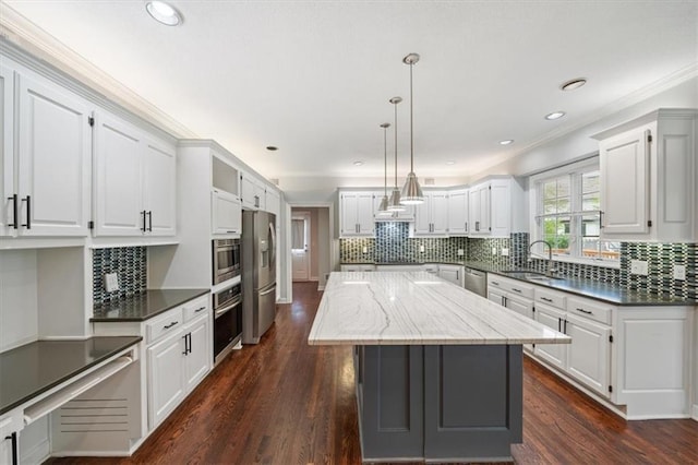 kitchen with crown molding, a center island, tasteful backsplash, a sink, and stainless steel appliances