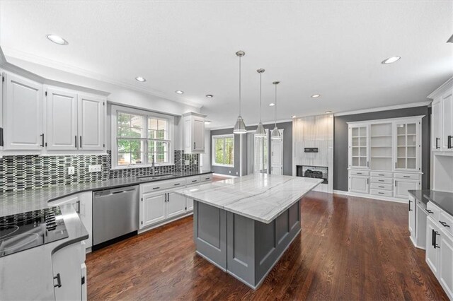 kitchen featuring crown molding, a center island, a large fireplace, a sink, and dishwasher