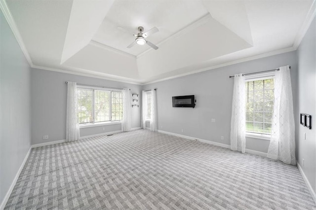 carpeted empty room featuring baseboards, ceiling fan, ornamental molding, and a tray ceiling