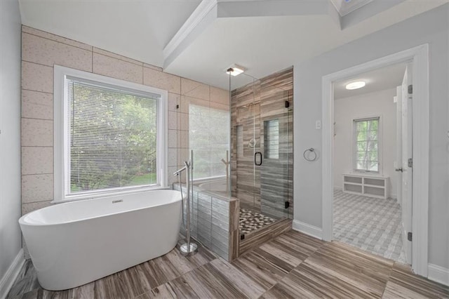 full bathroom with baseboards, a soaking tub, and a shower stall