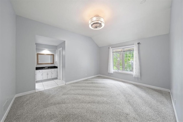 interior space featuring baseboards, light carpet, and lofted ceiling
