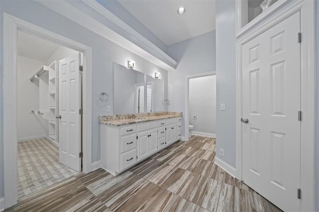 bathroom with double vanity, toilet, and baseboards