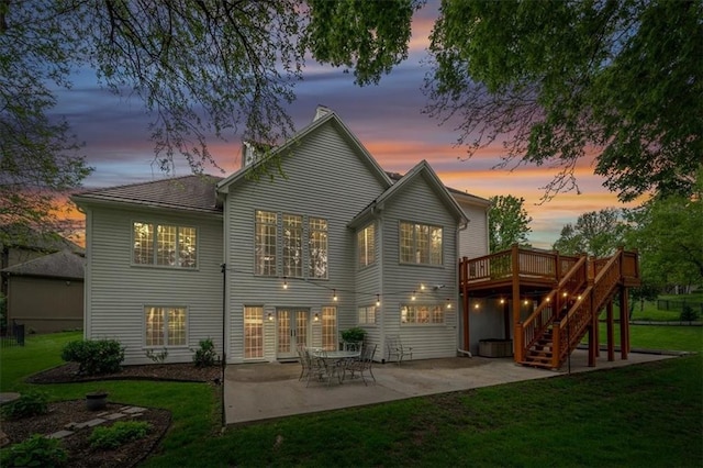 back of property at dusk featuring french doors, a lawn, a wooden deck, a patio area, and stairs