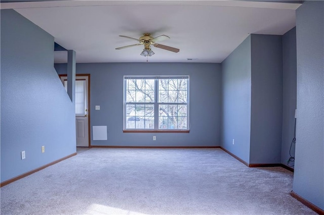 carpeted spare room featuring visible vents, baseboards, and ceiling fan