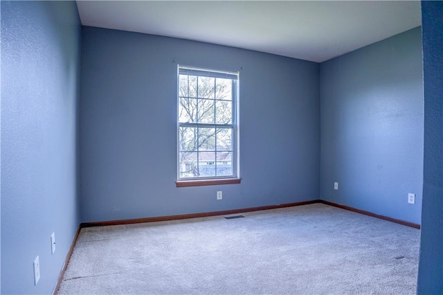 empty room with a healthy amount of sunlight, visible vents, baseboards, and carpet