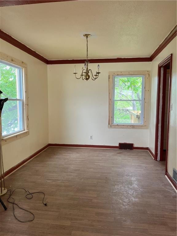 empty room with an inviting chandelier, ornamental molding, and wood finished floors