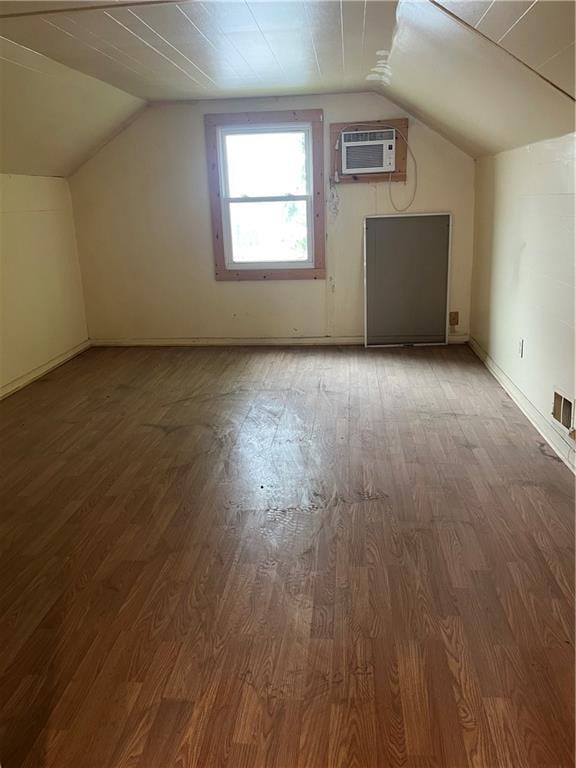 additional living space featuring wood finished floors, lofted ceiling, and a wall mounted AC