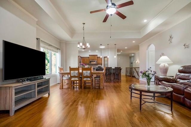 21287 W 116th St, Olathe, KS 66061 - living area with a raised ceiling, a ceiling fan, wood finished floors, crown molding, and arched walkways