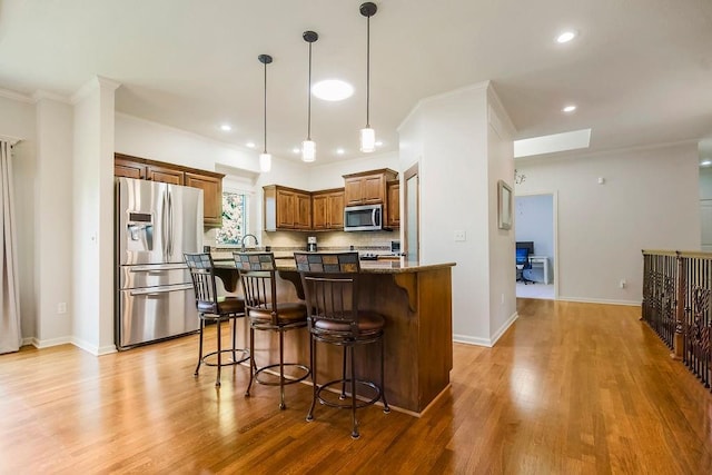 21287 W 116th St, Olathe, KS 66061 - kitchen with stainless steel appliances, crown molding, a kitchen breakfast bar, light wood-style floors, and a kitchen island