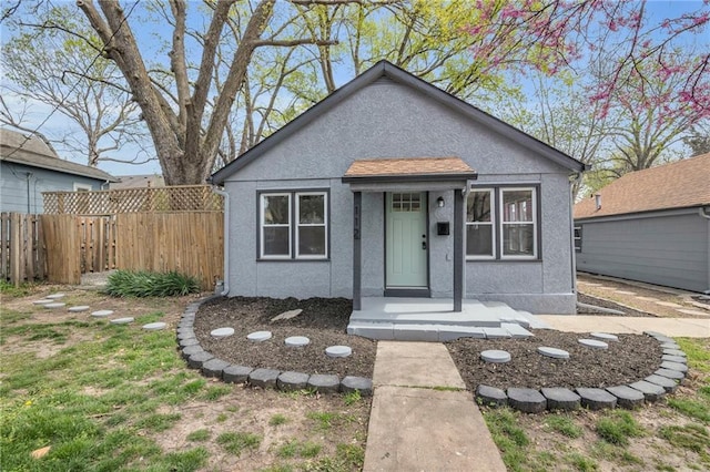 bungalow-style home featuring fence and stucco siding