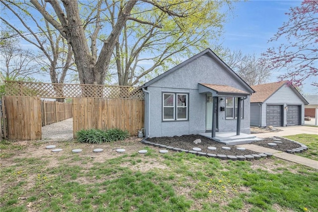 view of front of home featuring concrete driveway, stucco siding, an outdoor structure, and fence