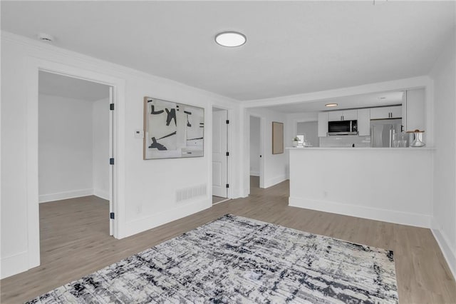 living area featuring visible vents, baseboards, crown molding, and wood finished floors