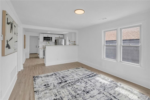 unfurnished living room with light wood-style flooring and baseboards