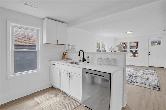 kitchen with dishwasher, a sink, light wood-style floors, a peninsula, and decorative backsplash