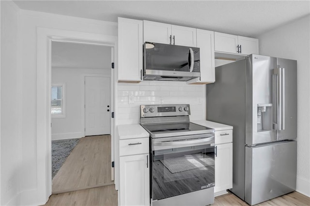 kitchen with stainless steel appliances, tasteful backsplash, light countertops, and white cabinetry