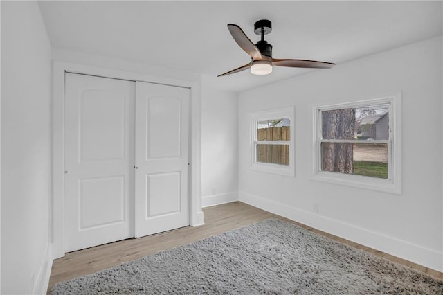 unfurnished bedroom with a closet, baseboards, ceiling fan, and wood finished floors