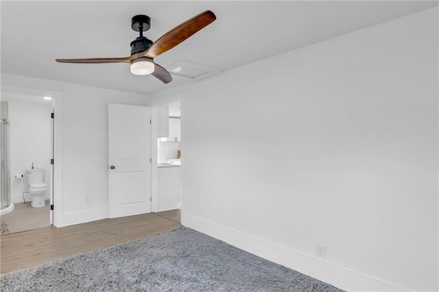 interior space with ensuite bathroom, baseboards, ceiling fan, and wood finished floors