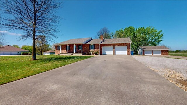 single story home featuring a front lawn, a garage, brick siding, driveway, and a chimney