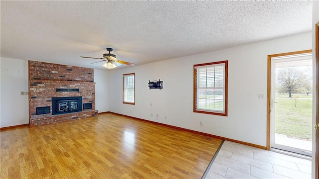 unfurnished living room featuring light wood finished floors, a textured ceiling, ceiling fan, and baseboards