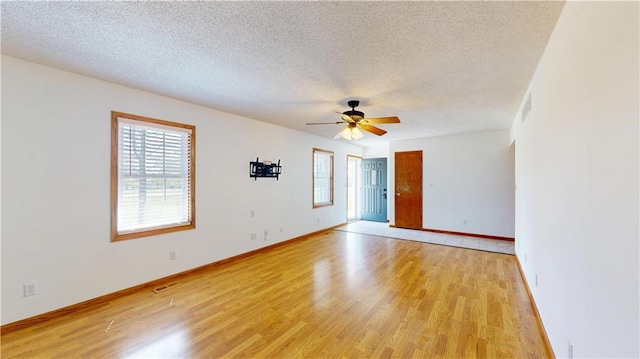 spare room with a textured ceiling, visible vents, a ceiling fan, and light wood-style flooring