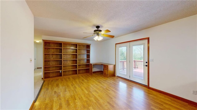 unfurnished room with a textured ceiling, light wood-style floors, a ceiling fan, and baseboards