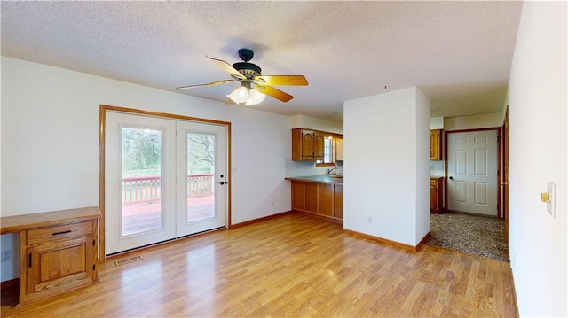 interior space featuring a ceiling fan, baseboards, a textured ceiling, and light wood-type flooring