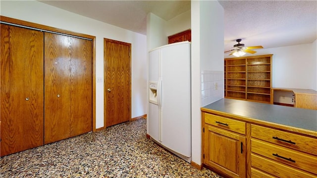 kitchen with brown cabinetry, a ceiling fan, and white refrigerator with ice dispenser