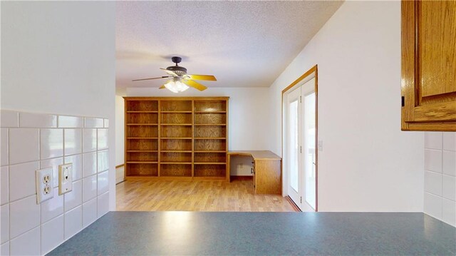 interior space with a textured ceiling, ceiling fan, and wood finished floors