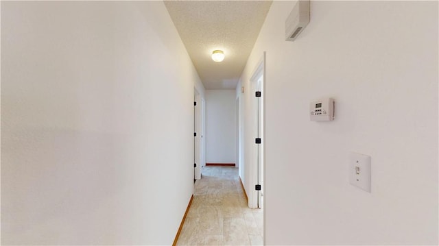 corridor featuring a textured ceiling and baseboards