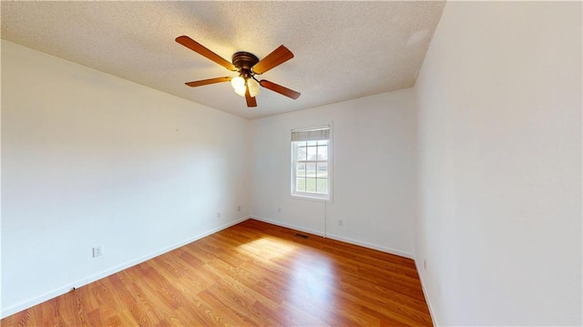 spare room featuring baseboards, ceiling fan, a textured ceiling, and light wood-style flooring