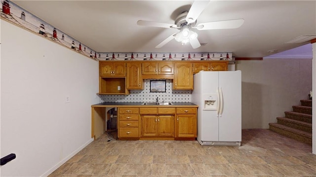 kitchen with brown cabinetry, ceiling fan, white refrigerator with ice dispenser, and a sink