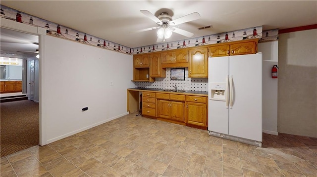 kitchen with visible vents, a ceiling fan, a sink, white fridge with ice dispenser, and brown cabinetry